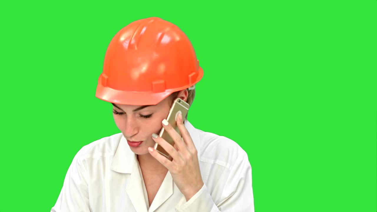 trabajador de la construcción mujer enojada en un casco gritando, hablando en el teléfono inteligente en una pantalla verde, clave de croma