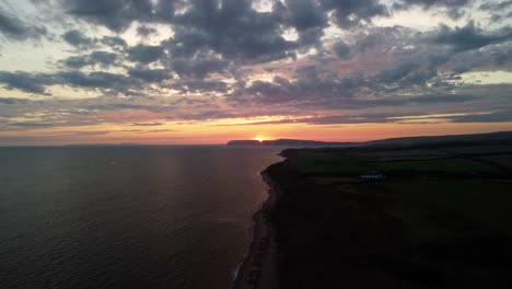 imágenes aéreas de drones 4k de alto sobre la costa de la isla de wight con el sol poniéndose en las colinas en el horizonte en la costa de la isla de wight