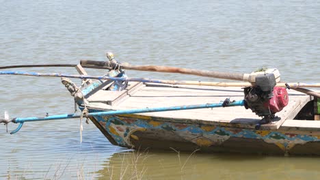 weathered boat with engine propeller resting out of water on river