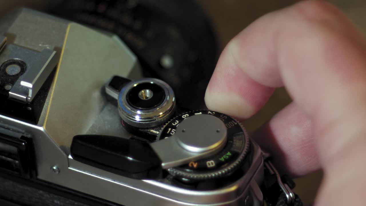 남자는 빈티지 35mm 필름 카메라의 셔터 속도 설정을 변경합니다.
