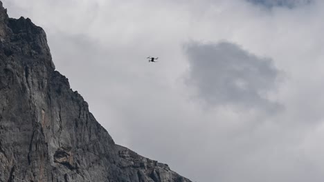 drone dji mini 3 pro hovering in the air and it does not move, detached from the cloudy sky and near a rocky mountain peak, switzerland