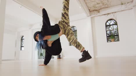 Caucasian-female-dancer-dancing-alone-and-wearing-hat-in-dance-studio,-slow-motion