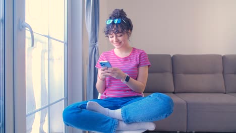 happy young woman typing message on mobile phone and listening to music in wireless headphones. cheerful white female using modern smartphone for communication. millenial person texting online