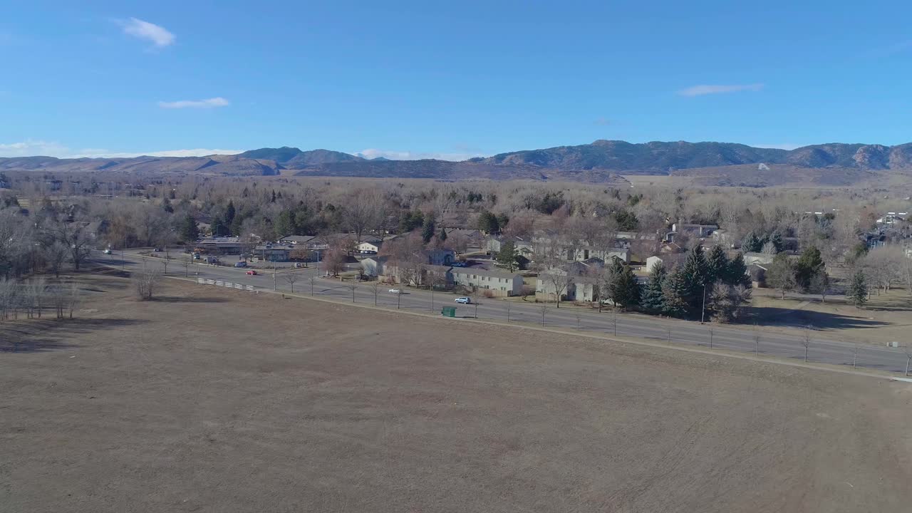 Penerbangan drone Fort Collins Colorado menghadap pegunungan berbatu pada pagi yang cerah, langit biru dan berkabut hangat di bulan Desember 2020 selama pandemi.