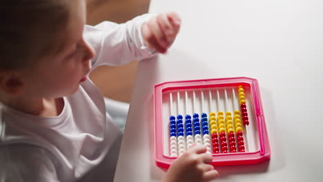 little schoolgirl does sums moving plastic beads on abacus