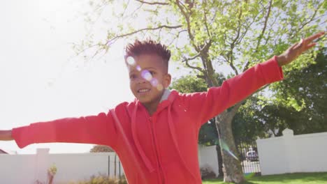 happy african american boy laying playing and smiling in garden