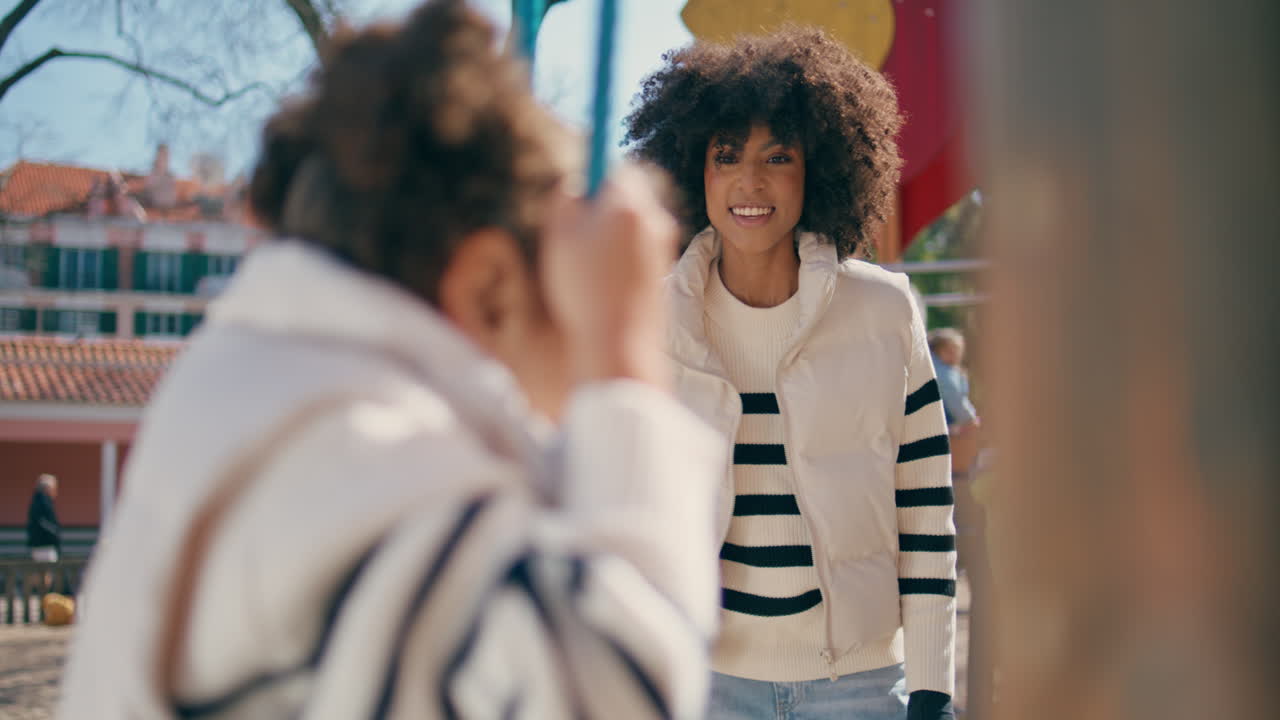 Little girl climbing rope ladder on playground close up. Mom looking kid