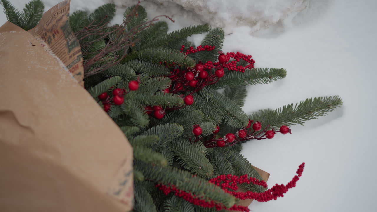 Festive evergreen bouquet on snow, brown paper wrap and bright red berries, frostdusted needles and rustic curbside composition, holiday present vibe ideal for florist delivery or romantic surprise