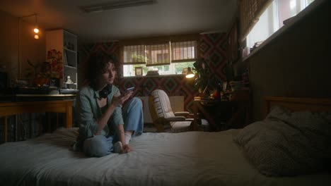 young woman using phone in a cozy bedroom