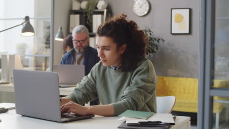 joven aprendiz trabajando en una computadora portátil en la oficina