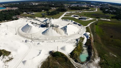 Drone-video-of-an-operating-sand-mine-where-trucks-are-loaded-with-material-for-delivery,-dolly-reveal