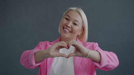 smiling woman making heart shape with hands