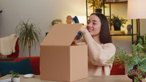 happy woman shopper unpacking cardboard box delivery parcel online shopping purchase headphones