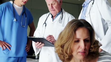 Nurse-and-doctor-discussing-over-clipboard-in-corridor-