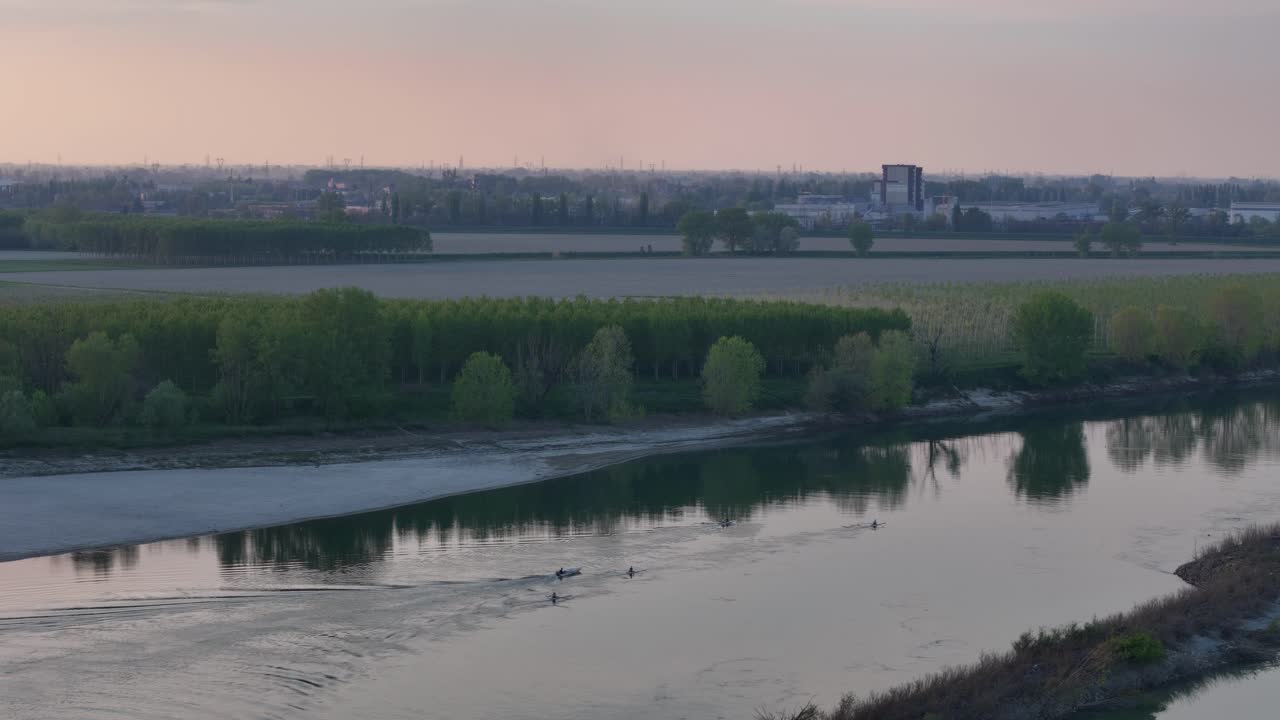 Rowing boats on the Po River near Cremona, their wakes trailing like flames across sunset-lit water, blending hydrodynamic rhythm with golden-hour reflection, Slow-motion drone shot
