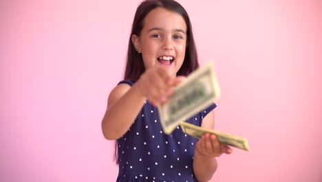 la pequeña niña caucásica recibe ingresos monetarios en billetes de dólar en efectivo. niño feliz divirtiéndose, sonriendo, mirando a la cámara.