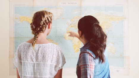 chicas turistas mirando el mapa del mundo planeando una aventura de viaje