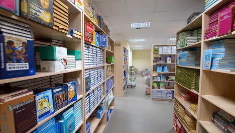 Library with big bookcase. Shot along shelves with paper books