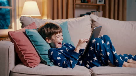 boy using tablet on couch