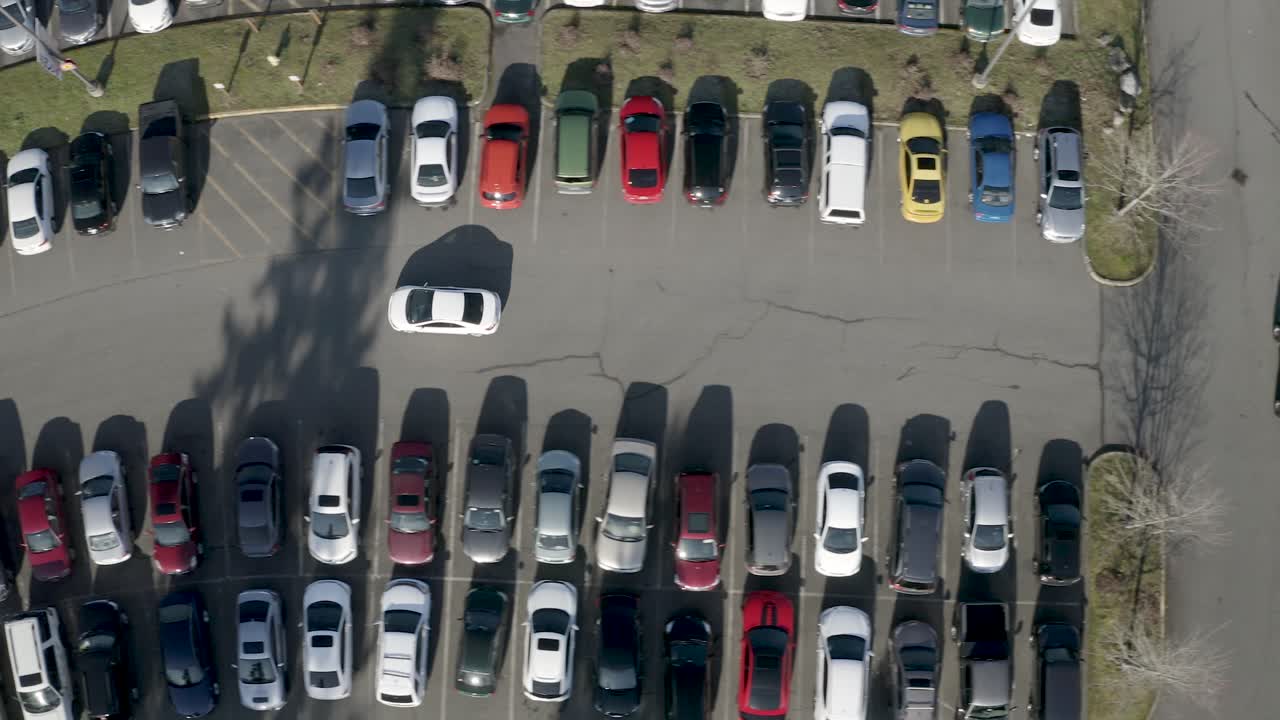Aerial View Of A White Car Searching For A Space In Parking Lot  - Aerial Shot