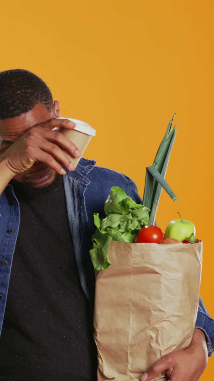Homem cansado bebendo café e segurando sacola de compras