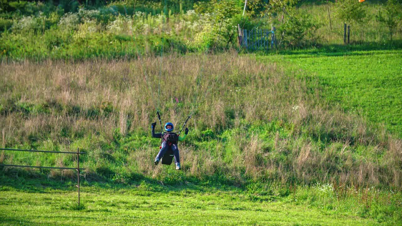 패러글라이더가 푸른 들판 위를 날아 착륙했다