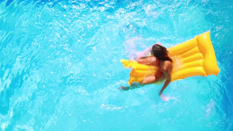 Overhead-of-brunette-sitting-on-lilo-in-pool-on-sunny-day