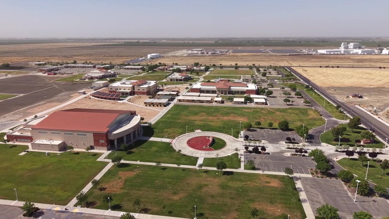 Ampia prospettiva aerea che cattura il moderno campus del West Hills College Lemoore, con la sua architettura distintiva, i prati verdi e il paesaggio agricolo circostante della Central Valley