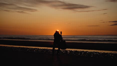 hombre corriendo con guitarra en la playa de arena trasera al atardecer-1