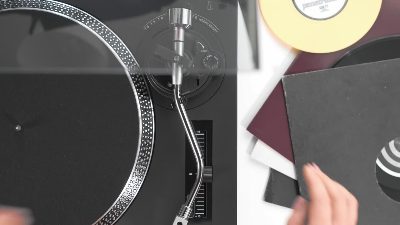 디제이의 소녀의 손에 사이드 뷰를 슬라이드하고, 회전 디스크에 검은 비닐 레코드를 넣고, 바늘, 스타일러스, 검은 헤드폰을 넣습니다.