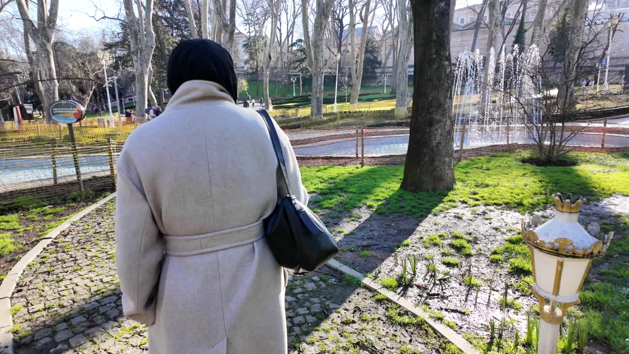 Kvinna som promenerar på en kullerstensstig i en solig park