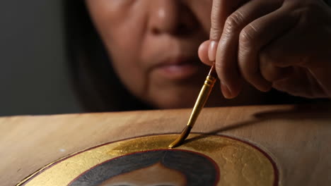 artist painting a religious icon with gold leaf