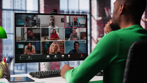 african american guy at desk is engaged in video call with coworkers