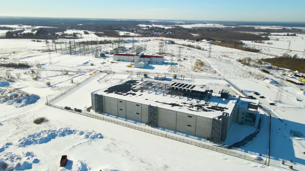 Høj luftoptagelse, der afslører et moderne modulopbygget datacenters ydre og en højspændingsunderstation, der opererer i et sneklædt vinterlandskab, og som understøtter pålidelig skyinfrastruktur. Storstilet serveranlæg