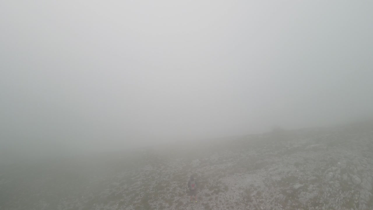 몬테네그로의 두꺼운 구름과 함께 산 꼭대기에 있는 사람의 궤도 전망