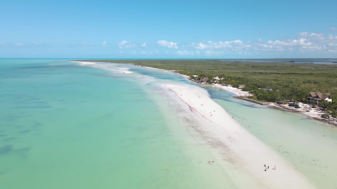 Wide angle drone shot off the coast of the tropical island of Holbox located in the Caribbean sea with crystal clear turquoise waters and white sand beaches in Mexico shot in 4k