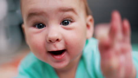 happy cheerful resilient baby boy lies on belly in front of camera. face portrait of a lovely child with plump cheeks.