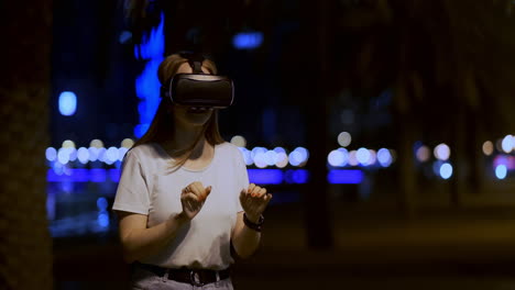 A-young-girl-in-virtual-reality-glasses-in-a-large-metropolis-simulates-work-in-the-program-game-virtual-reality-interface.-The-concept-of-augmented-reality