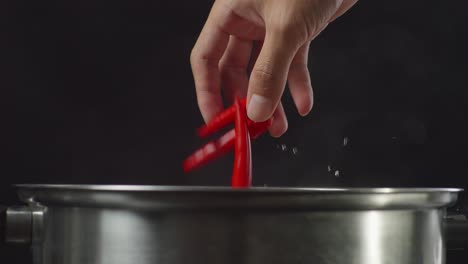 añadiendo chiles y sal a una olla