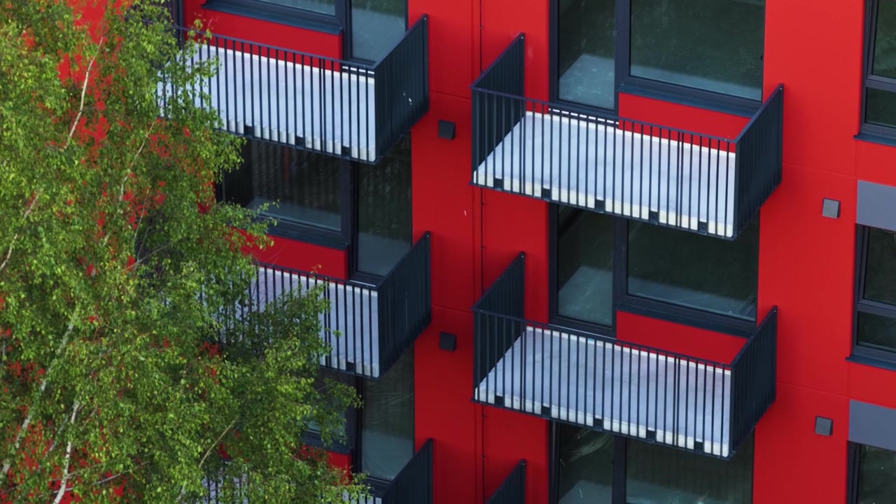 Edifício residencial moderno com fachada vermelha vibrante e design de varanda contemporâneo