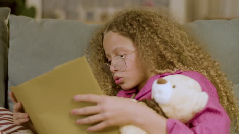 closeup of young cute girl sitting on couch reading book at home