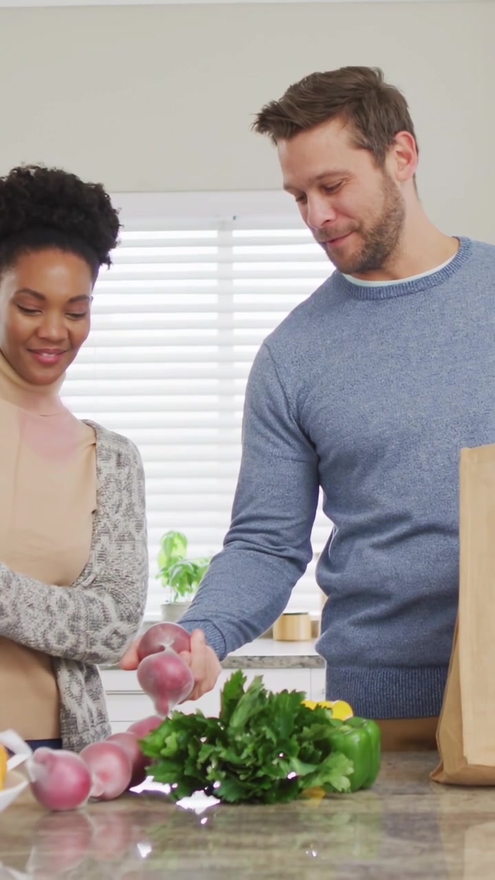 Video vertical: Pareja en la cocina desempacando, hombre metiendo la mano en una bolsa, burbujas moradas ayudando en la preparación de comidas