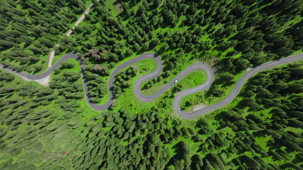 Top down drone shot of a car driving along the iconic snake road of Giau Pass in the Dolomites, Italy