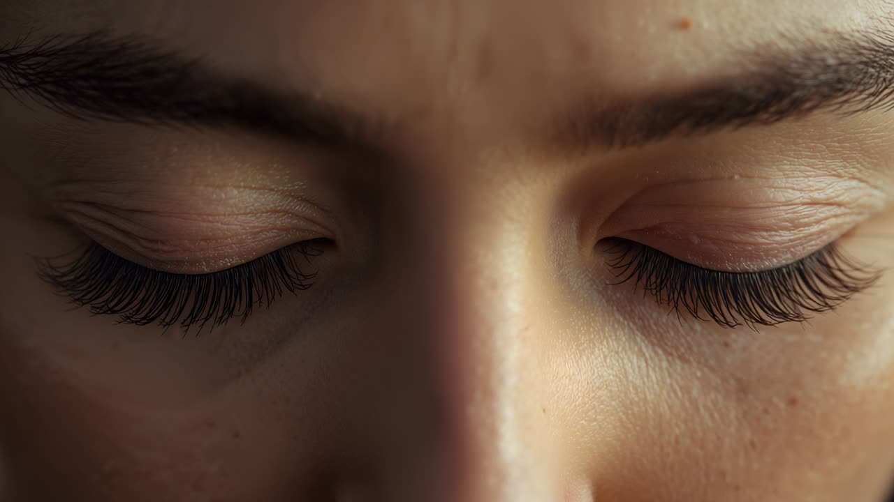 Reacting to warm light, woman opening eyelids in studio close-up, revealing brown irises and lashes