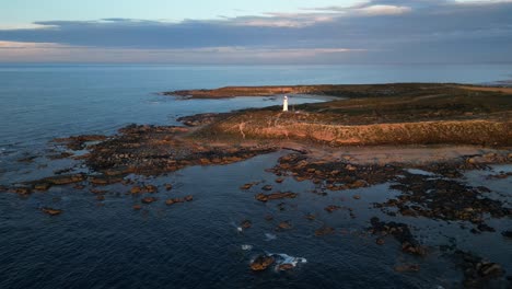 a beautiful lighthouse during sunset, from the perspective of a drone