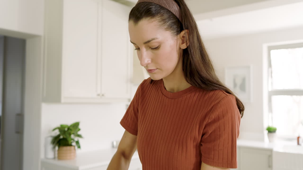 Woman in kitchen preparing meal, wearing casual attire, enjoying cooking process