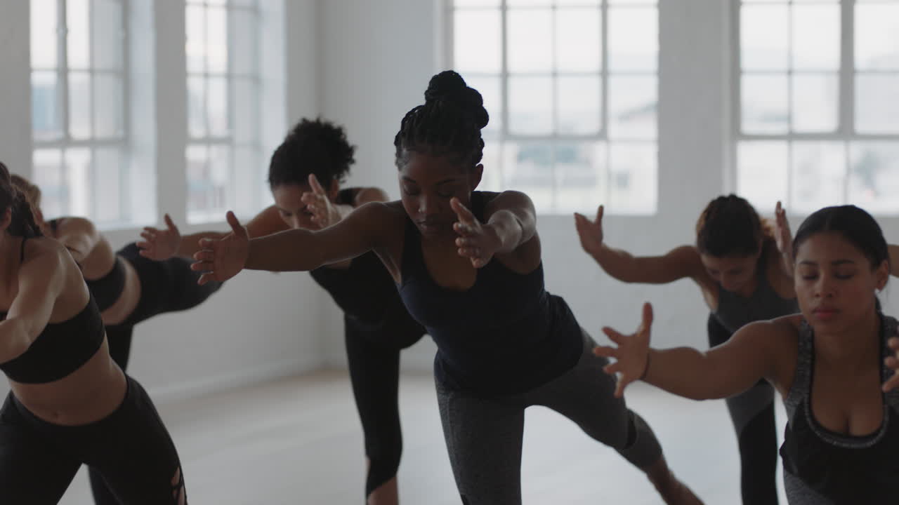 yoga class group of multiracial women practicing warrior pose enjoying healthy lifestyle exercising in fitness studio at sunrise