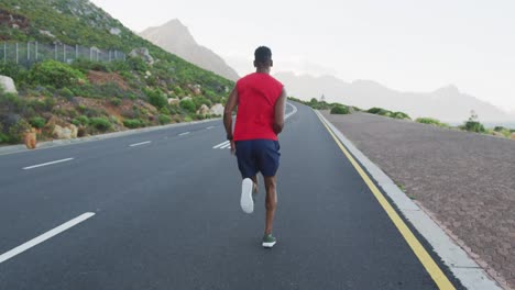 Hombre-Afroamericano-Haciendo-Ejercicio-Al-Aire-Libre-Corriendo-Por-Una-Carretera-Costera