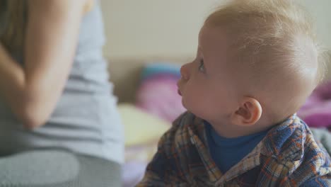 Kleiner-Junge-Im-Hemd-Kriecht-Bei-Mama-Im-Geräumigen-Zimmer-Auf-Dem-Bett