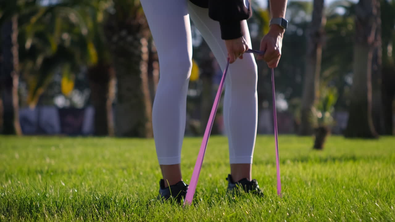 야외에서 저항 밴드로 다리 운동을 하는 여자